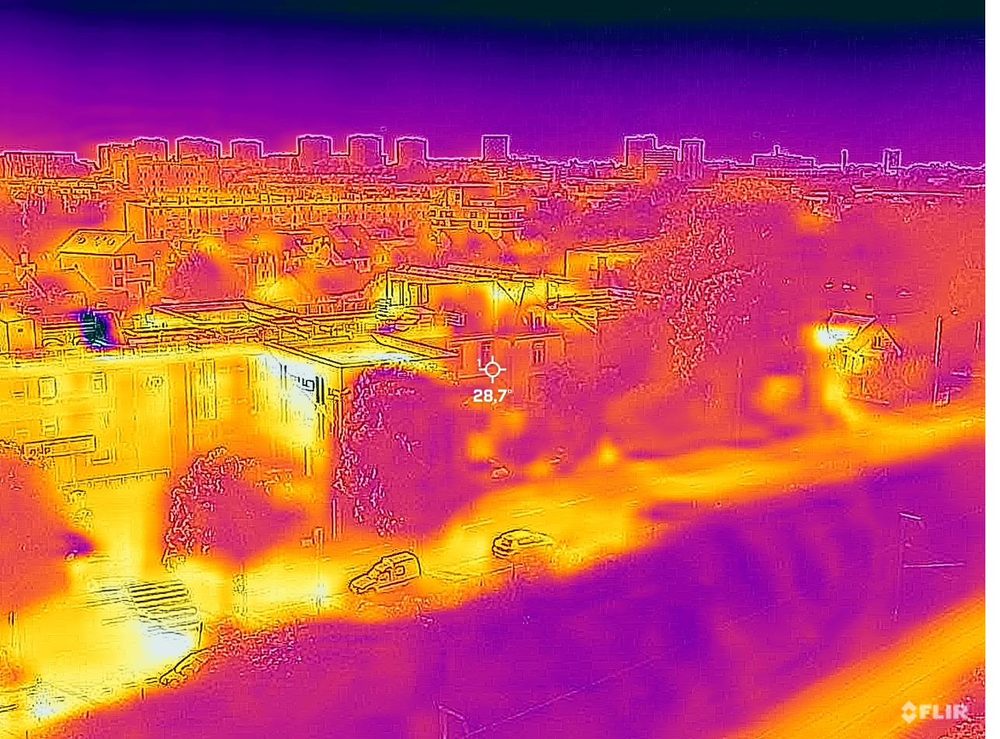 La même scène en thermographie : surfaces minérales chaudes, végétation fraîche